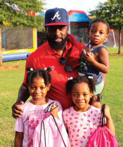 Councilman Cleo King poses with kids from backpack giveaway event