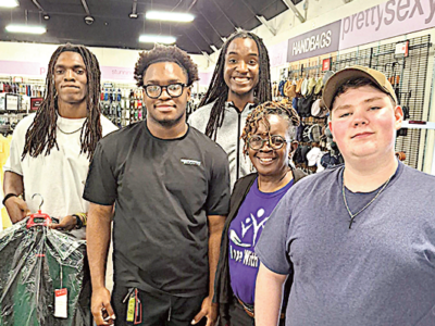 Ms. Hill smiles with male students who received prom suits.